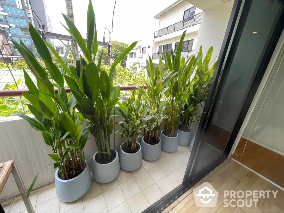 Charming balcony with lush potted plants and sliding glass door, perfect for relaxation.