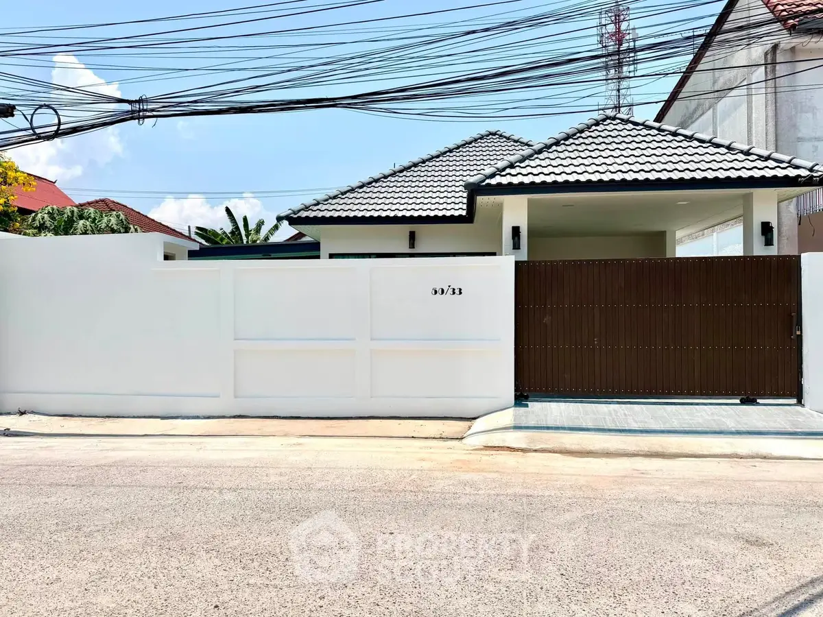 Charming single-story home with modern roof design and secure gated entrance in a serene neighborhood.