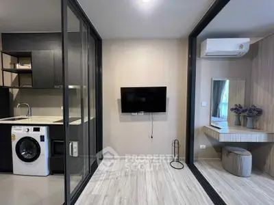 Modern apartment with sleek kitchen and cozy living area featuring washing machine and wall-mounted TV.
