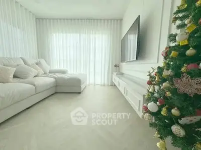 Spacious living room with elegant decor and Christmas tree, featuring a large sofa and wall-mounted TV.