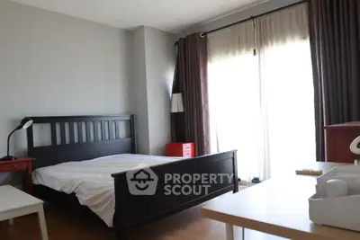 Spacious bedroom with modern furnishings and natural light from large windows.