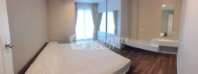 Spacious modern bedroom with large windows and stylish wooden flooring.