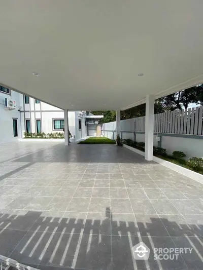 Spacious modern carport with tiled flooring and garden view in contemporary home.