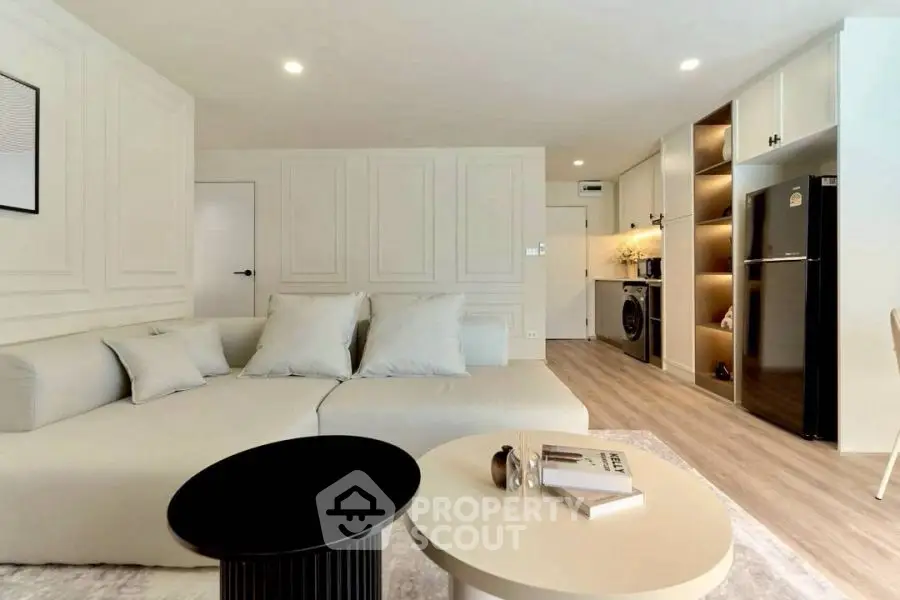Modern living room with sleek design, cozy sofa, and integrated kitchen appliances.