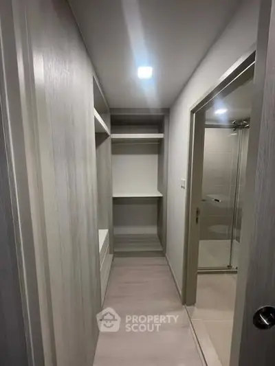 Spacious walk-in closet with modern shelving and adjacent bathroom entry.