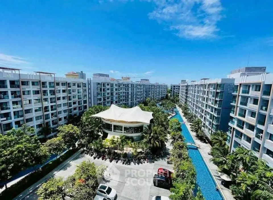 Stunning aerial view of modern apartment complex with lush greenery and pool.