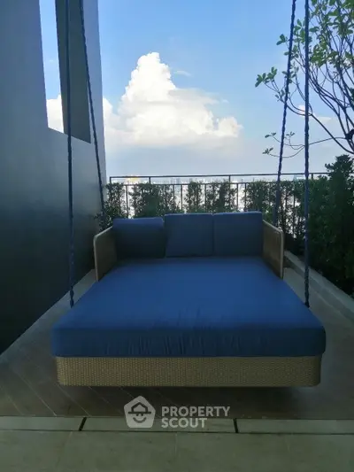 Luxurious balcony with a stylish outdoor swing bed and lush greenery, perfect for relaxation and enjoying the view.