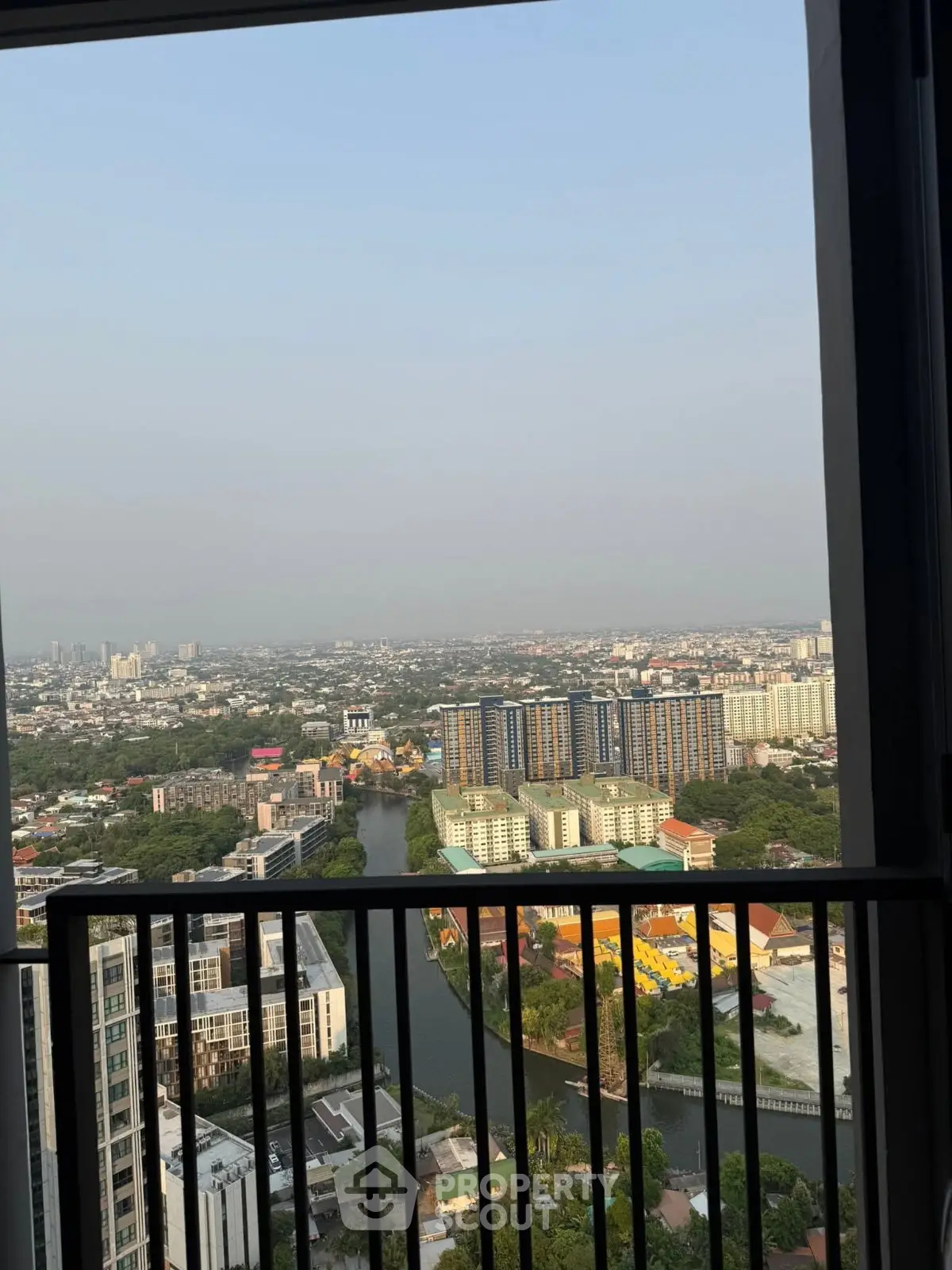 Stunning high-rise view from a balcony overlooking a vibrant cityscape and river.