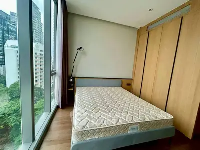 Modern bedroom with large window and city view, featuring a minimalist design and wooden accents.