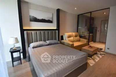 Modern studio apartment with stylish decor and cozy furnishings, featuring a comfortable bed and compact kitchen area.