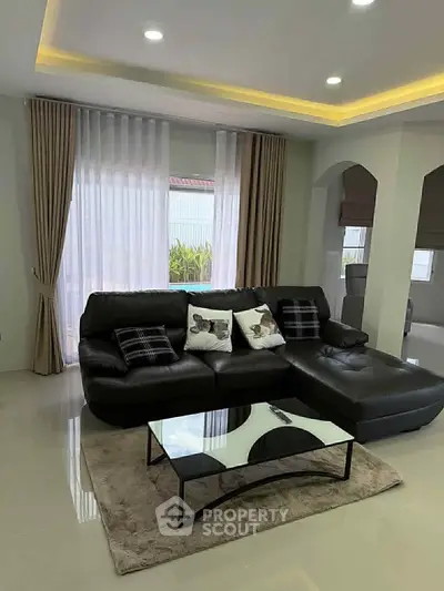 Modern living room with sleek black leather sofa and stylish glass coffee table.