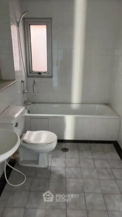 Spacious bathroom with bathtub and natural light from window