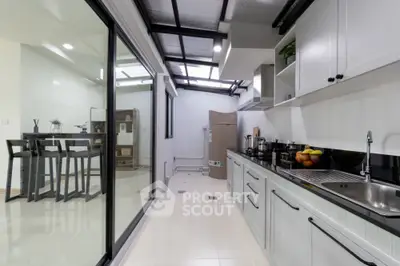 Sleek modern kitchen with high-gloss cabinetry and stainless steel appliances, opening to a spacious dining area with abundant natural light.