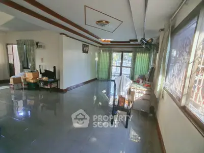 Spacious living room with large windows and glossy tiled floors in a cozy home.
