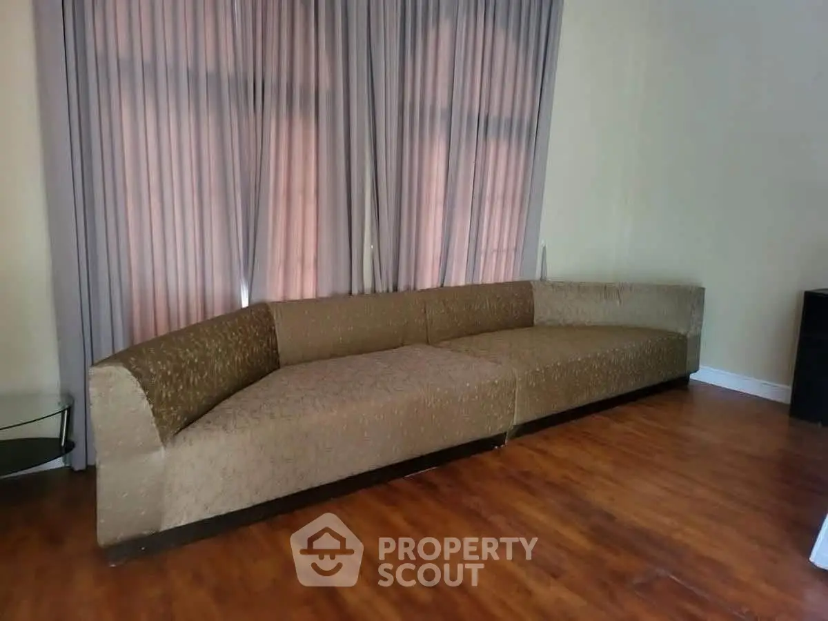 Spacious living room with elegant curved sofa and hardwood flooring
