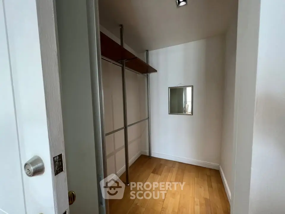 Spacious walk-in closet with wooden flooring and ample hanging space.
