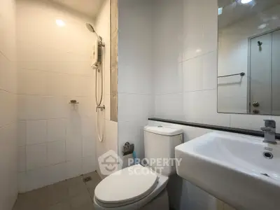 Modern bathroom with sleek fixtures and white tiles, featuring a shower and toilet.