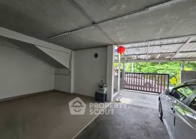 Spacious garage with car and open gate leading to lush greenery.