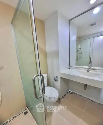 Modern bathroom with glass shower and sleek vanity in a contemporary apartment.