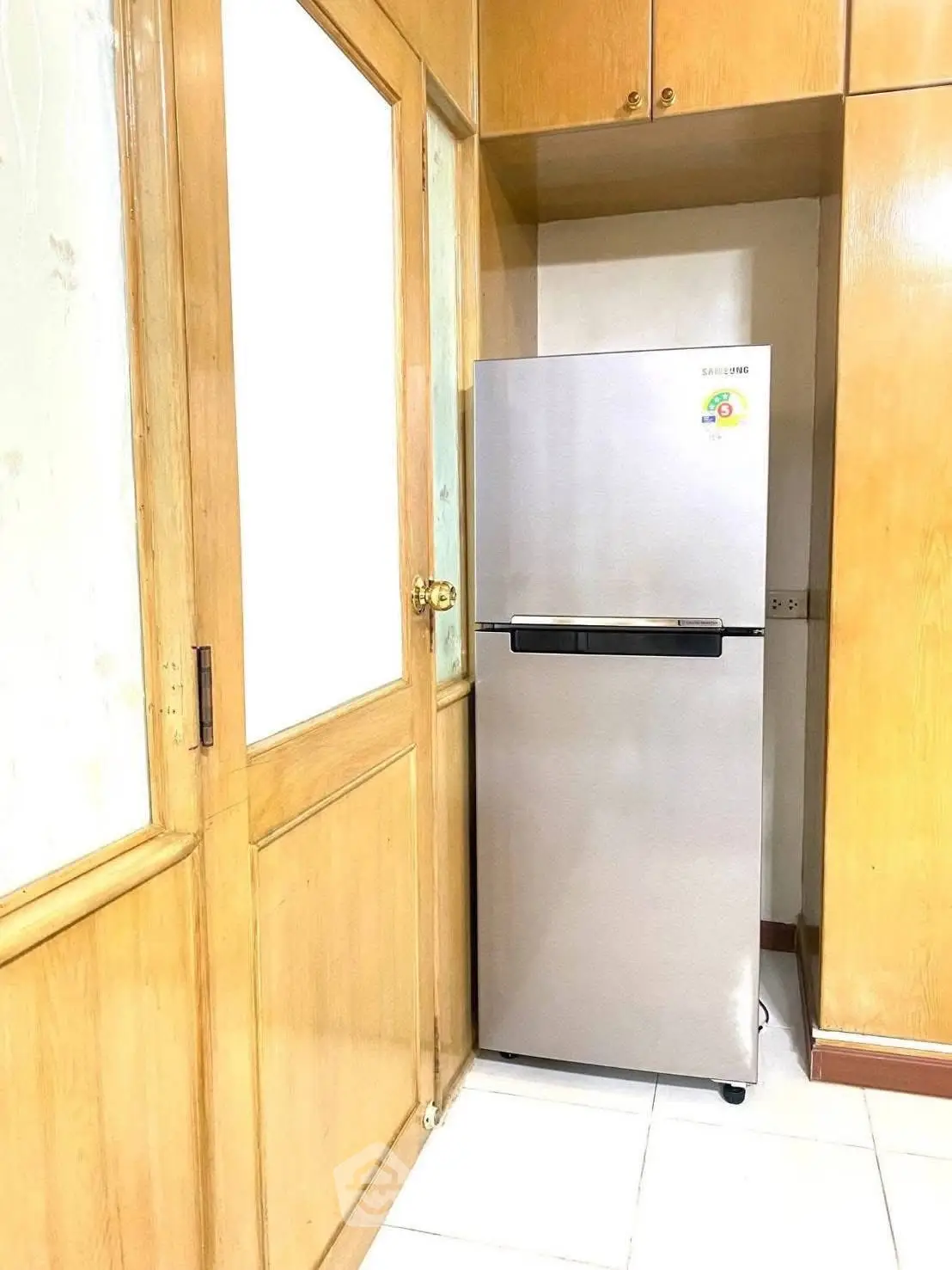 Modern kitchen corner with sleek stainless steel fridge and wooden cabinetry.