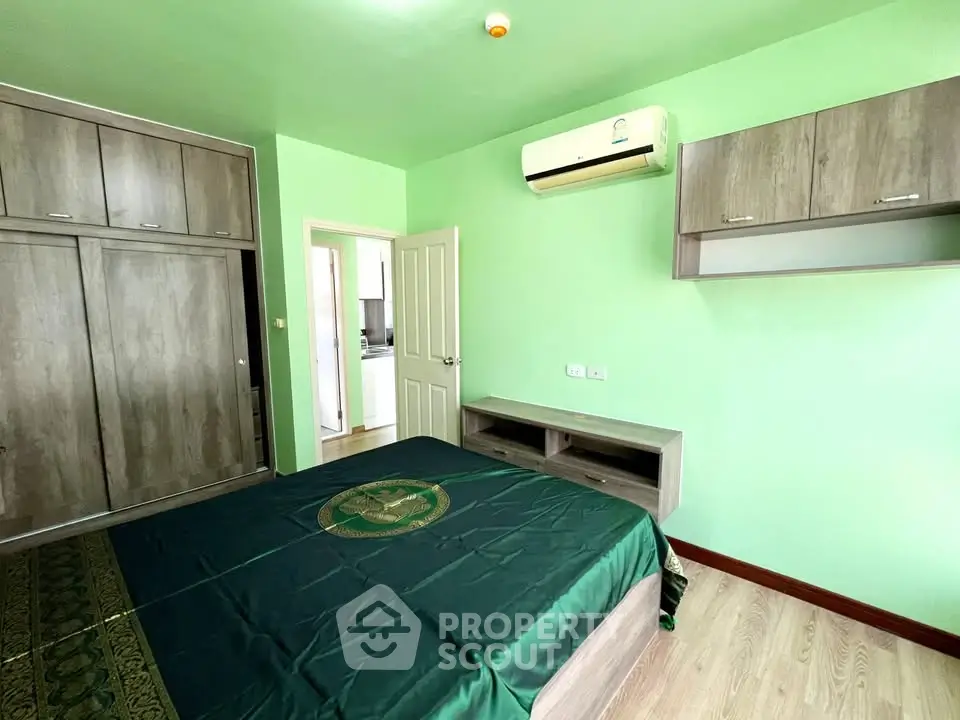 Spacious bedroom with modern furnishings and air conditioning in a vibrant green color scheme.