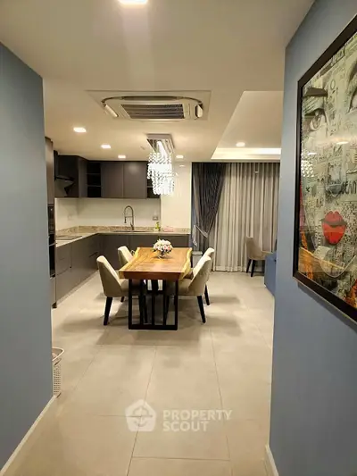 Modern dining area with elegant chandelier and open kitchen layout in a stylish apartment.