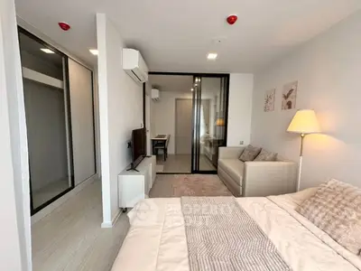 Modern bedroom with cozy decor and sliding glass doors leading to a study area, featuring neutral tones and stylish furnishings.