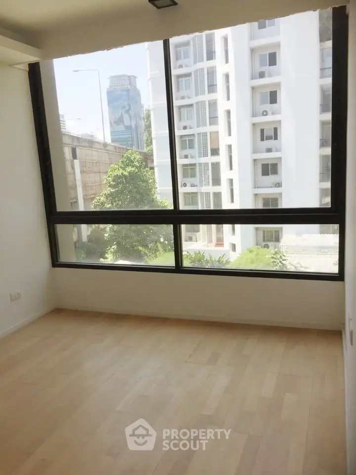 Bright empty room with large window and city view, perfect for customization.