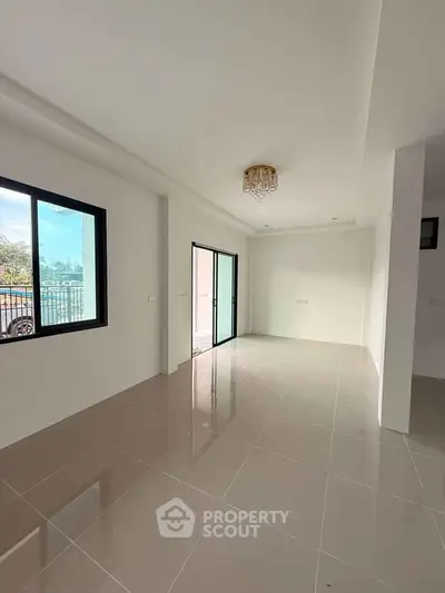 Spacious living room with large windows and elegant chandelier in modern apartment.