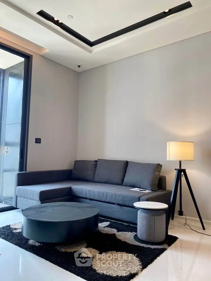 Modern living room with sleek gray sofa, stylish lamp, and contemporary decor.