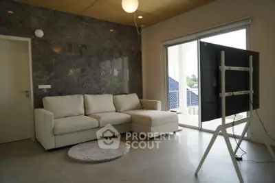 Modern living room with sleek design, featuring a comfortable sofa and large TV, opening to a balcony with scenic views.
