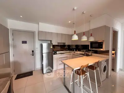 Modern kitchen with sleek appliances and stylish island seating in a contemporary apartment.