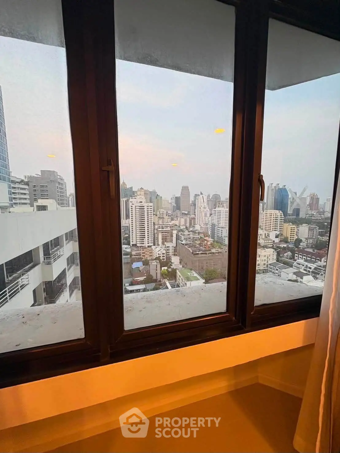 Stunning cityscape view from a high-rise apartment window, showcasing urban skyline and modern architecture.
