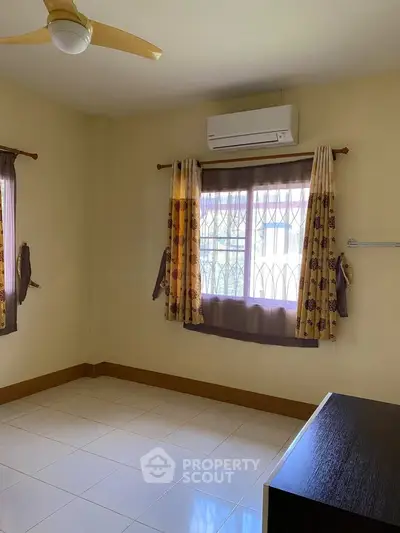Spacious bedroom with air conditioning and large windows for natural light.