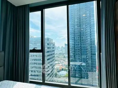 Stunning city view from a modern high-rise bedroom window, offering a glimpse of urban luxury living.