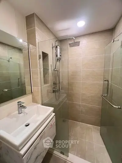 Modern bathroom with glass shower enclosure and sleek vanity in contemporary design.