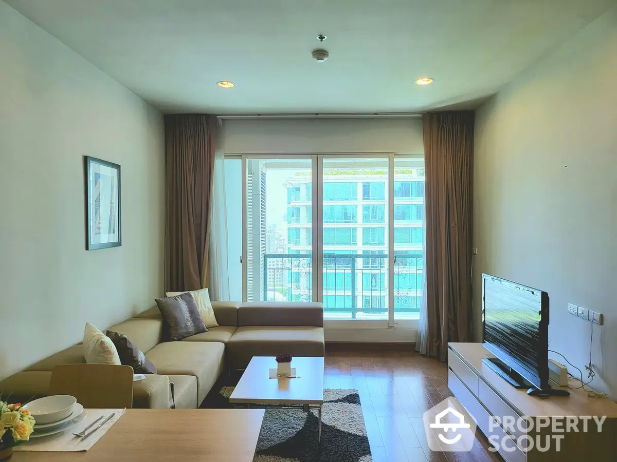 Spacious living room with modern furnishings, ample natural light, and access to a large balcony offering an urban view, perfect for entertaining or relaxation.