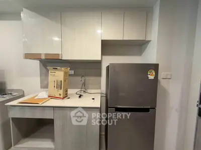 Modern kitchen with sleek cabinetry and stainless steel fridge in a compact layout.
