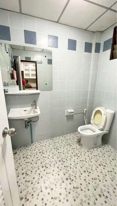 Modern bathroom with tiled walls and floor, featuring a toilet and sink.