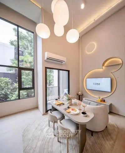 Modern living room with high ceilings, stylish lighting, and large windows offering a serene garden view.