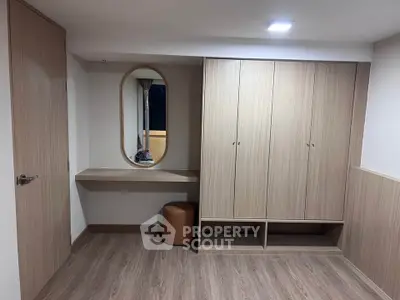 Modern bedroom with sleek wooden wardrobe and stylish oval mirror