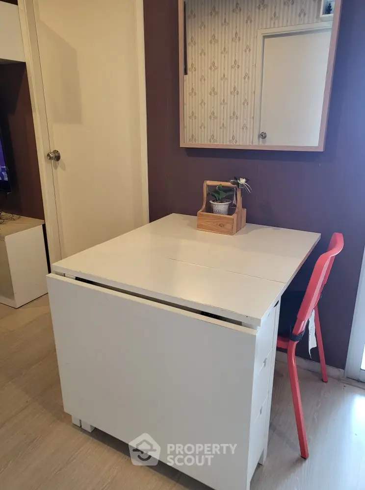 Cozy interior space with a foldable white table and red chair, perfect for compact living.