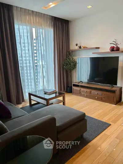 Modern living room with large TV, cozy sofa, and elegant decor.