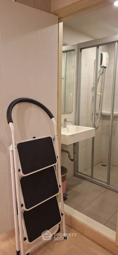 Compact bathroom with shower and step ladder in modern apartment