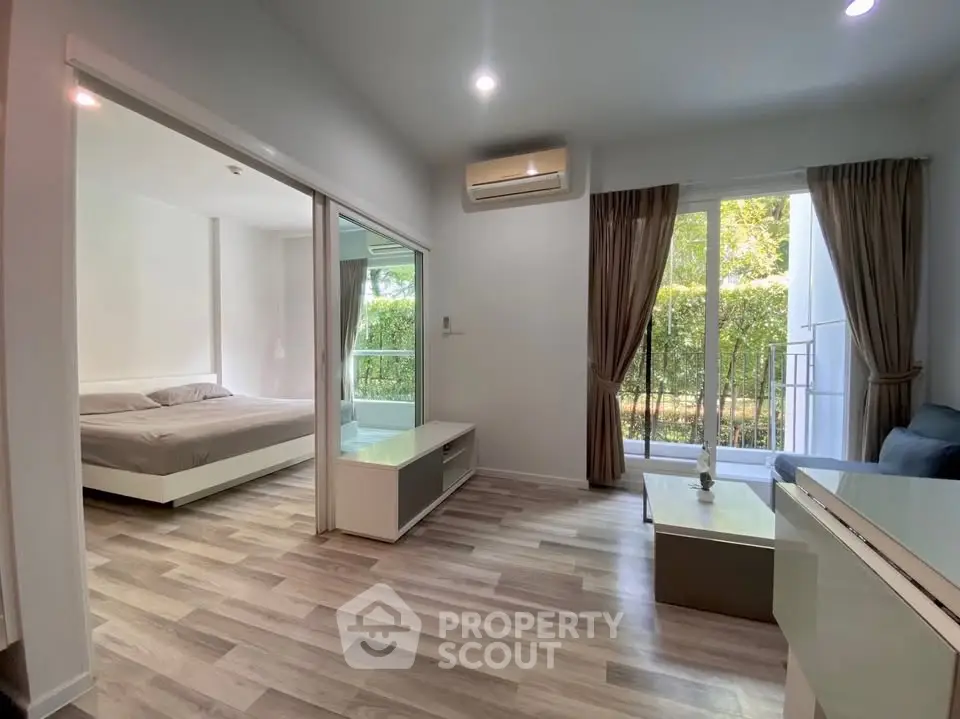 Modern open-plan living room with bedroom view and balcony access in stylish apartment.
