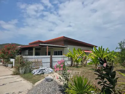 Charming single-story house with lush garden and spacious yard under a clear blue sky.