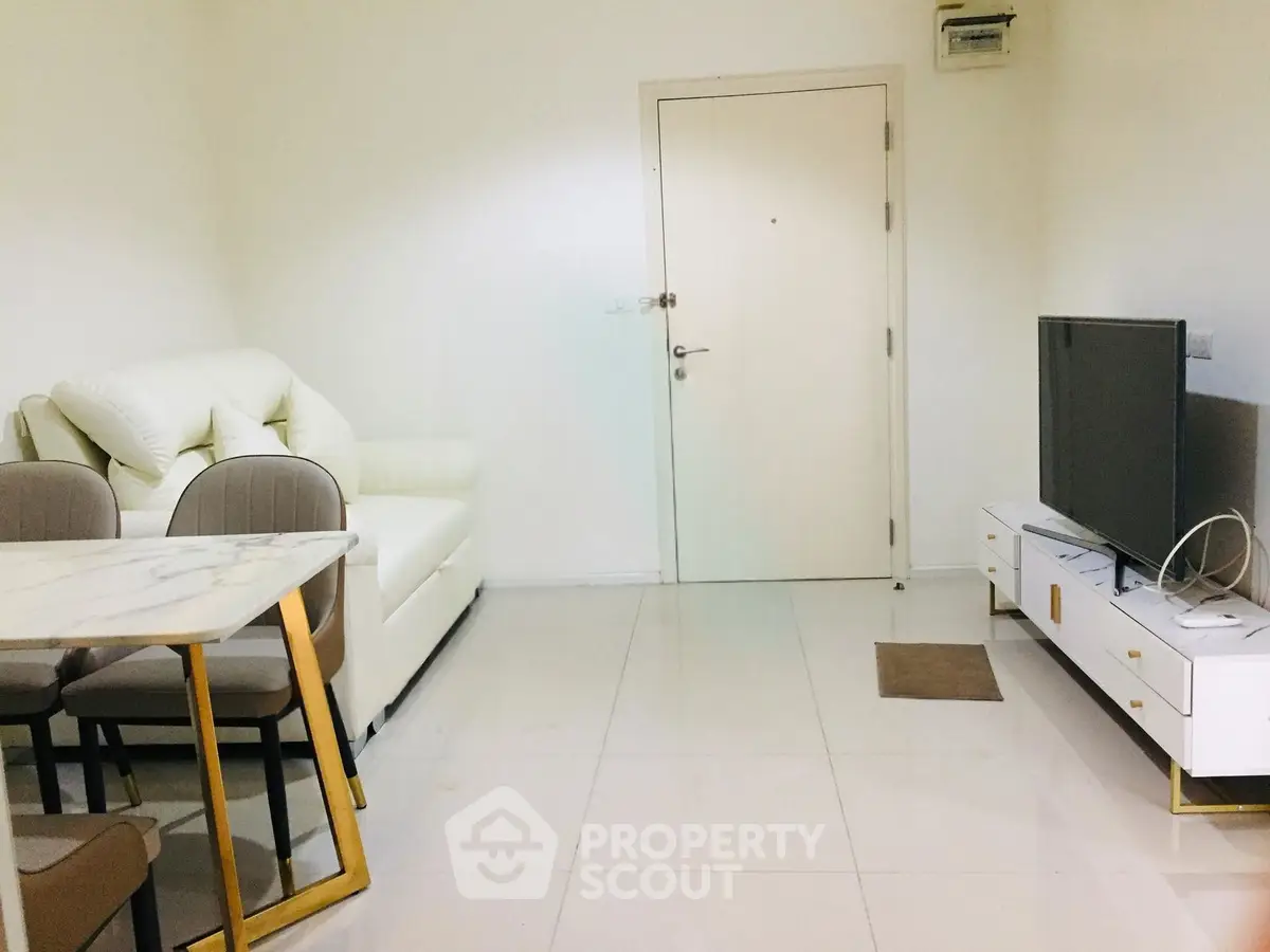 Modern living room with white sofa, TV unit, and dining table in a cozy apartment.