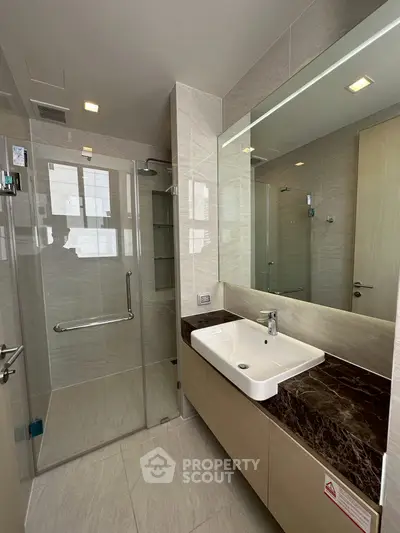 Modern bathroom with glass shower and sleek vanity in luxury apartment