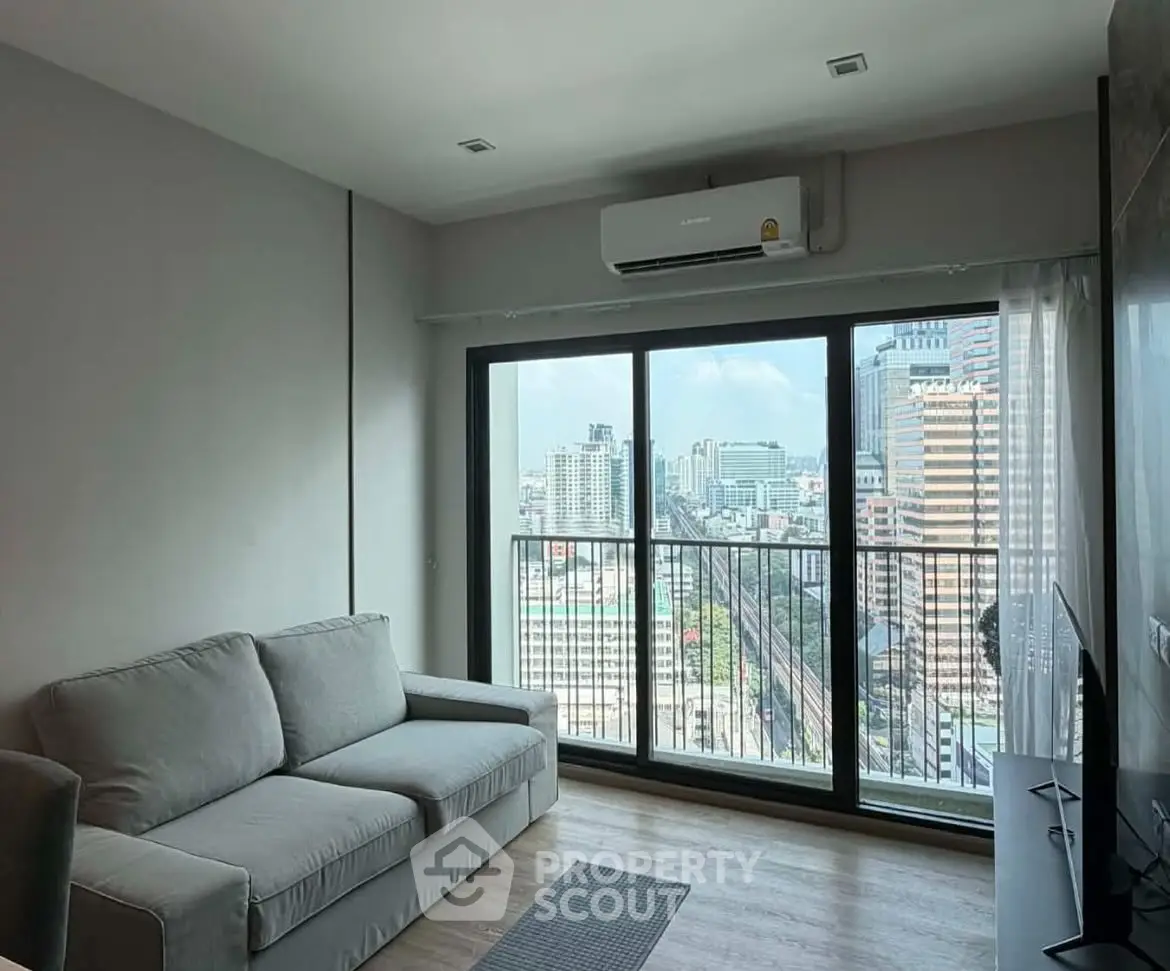 Modern living room with city view from large windows and cozy sofa.
