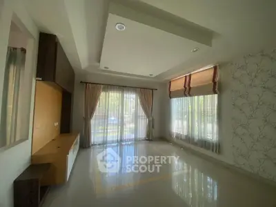 Spacious living room with large windows and elegant curtains, perfect for natural light.